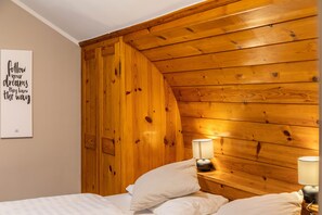 A bedroom with a wooden sloped ceiling, a bed with white bedding, two bedside lamps, and a motivational quote on the wall. - Room 16 (budget double room) with mountain view, balcony and Wi-Fi (Seefeld in Tirol)
