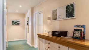 A hallway with a wooden counter, framed pictures, and a book titled 'Hunderwasser'. - Room 12 (single room) with mountain view, balcony and Wi-Fi (Seefeld in Tirol)
