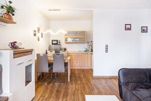 Een moderne keuken met een eetgedeelte, houten vloeren en een zwarte leren bank.