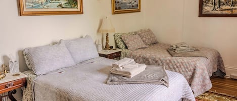 A hotel room with two beds, a nightstand, a lamp, and a rug.