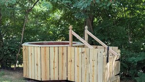 A wooden hot tub structure with a sloped roof, surrounded by a natural forest setting. - The Gould Residence (Seneca Falls)