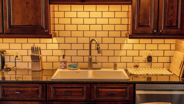 A kitchen with wooden cabinets, a sink, and a dishwasher. - The Gould Residence (Seneca Falls)