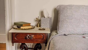 A bedside table with a book, a tissue box, and a decorative item. - The Gould Residence (Seneca Falls)