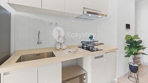 Een moderne keuken met witte kasten, een roestvrijstalen spoelbak en een inbouwoven en klein fornuis.
