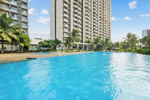 Une piscine offrant une vue sur de grands immeubles résidentiels et des palmiers.