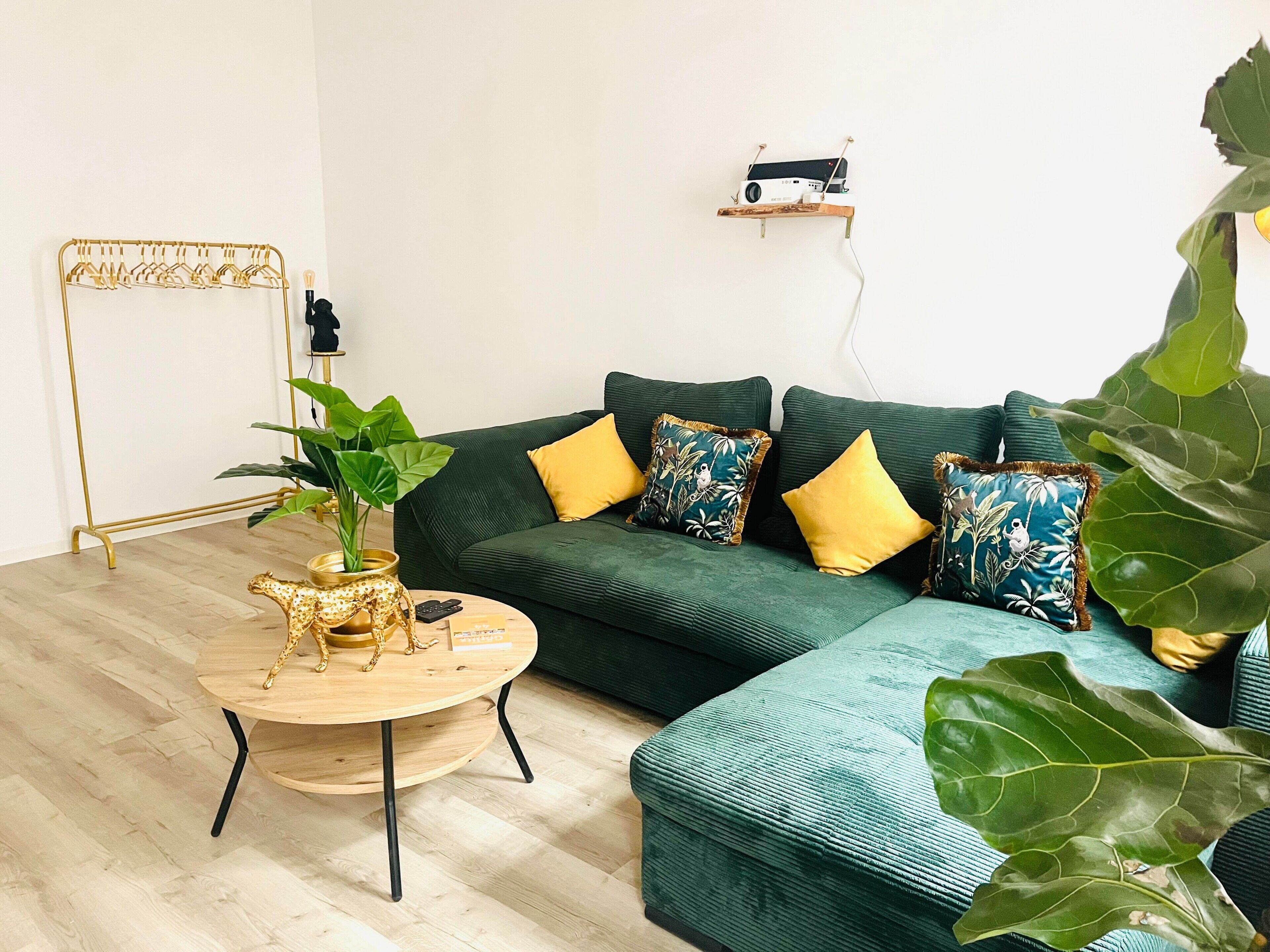 A modern living room with a green sofa, yellow cushions, a wooden coffee table, and a plant.