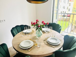 Una mesa redonda de comedor con un jarrón de rosas rosadas, posavasos dorados y vasos de cristal.