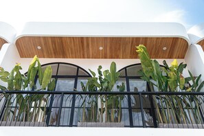 Un edificio moderno con techo de madera y un balcón con plantas altas.