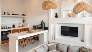 A modern kitchen with a central island, wooden chairs, a built-in oven, and a flat-screen TV mounted above the island. - the macan Canggu (Canggu)