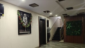 A hallway with a framed portrait, a staircase, and a green wall panel. - sai balaji residency (Rahata)