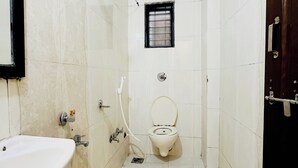 A small, narrow bathroom with a toilet, sink, and shower. - sai balaji residency (Rahata)