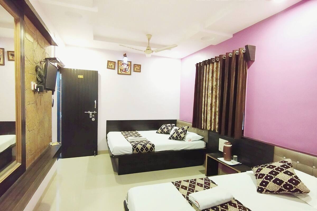 A hotel room with two beds, a large mirror, a ceiling fan, and a window with curtains.