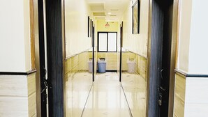 A long, narrow hallway with doors on both sides, a trash bin in the center, and a tiled floor. - sai balaji residency (Rahata)