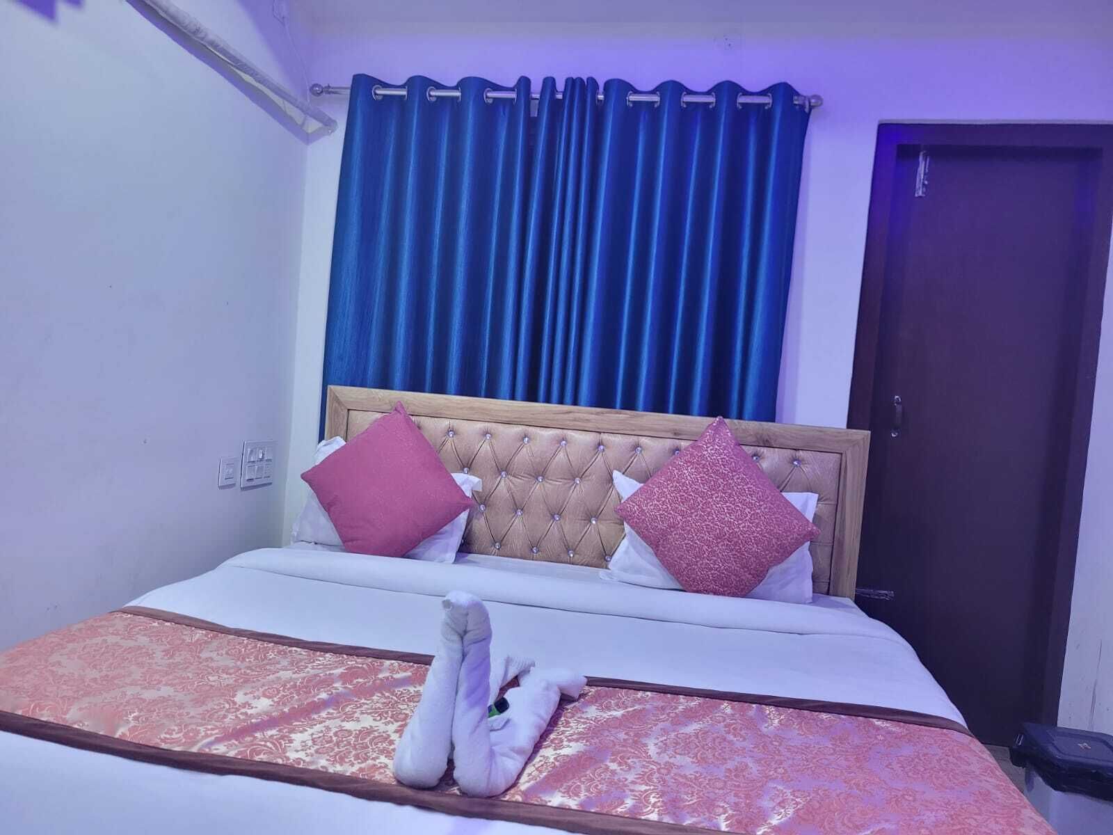 Una cama bien hecha con una colcha estampada, dos almohadas y un par de toallas dobladas sobre la cama.