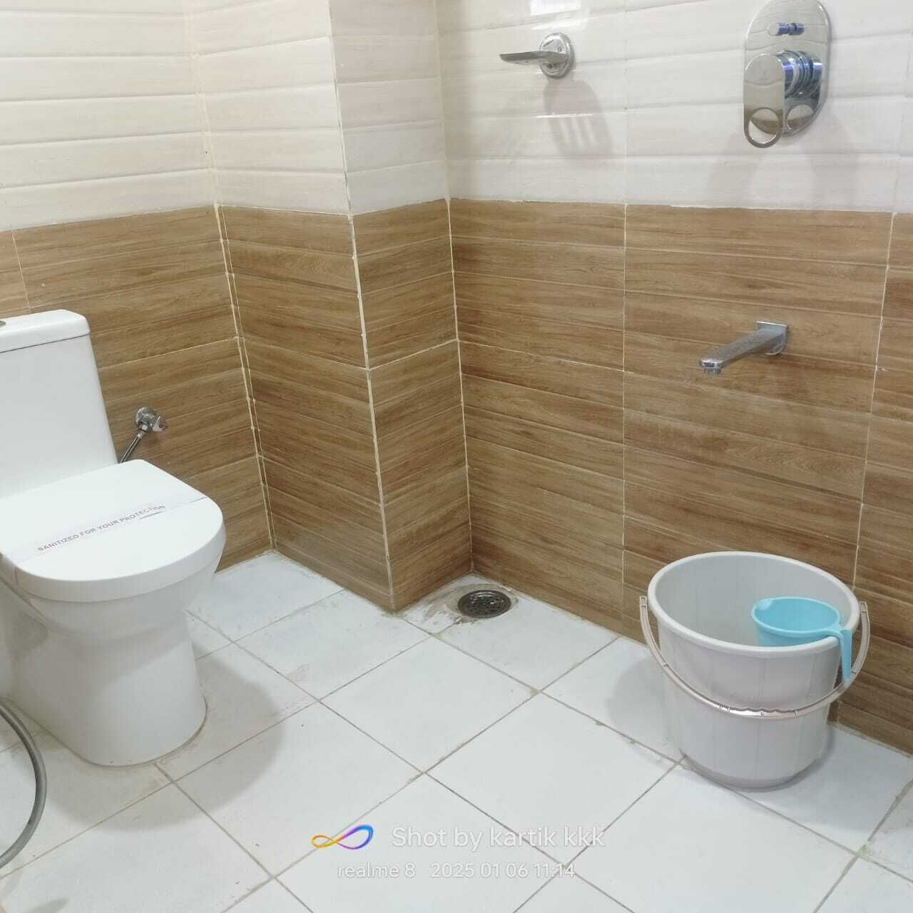 A bathroom with a toilet, a shower, and a bucket.