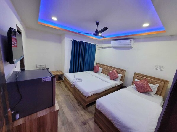 A hotel room with two beds, a TV, and an air conditioning unit. - Pavilion City Hotel (Nagaon)