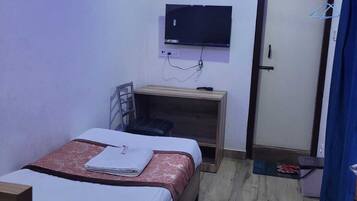 Una habitación de hotel con una cama, un escritorio, un televisor y un equipo de aire acondicionado.
