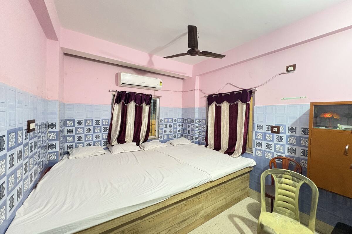 A bedroom with a single bed, a ceiling fan, and a window with curtains.
