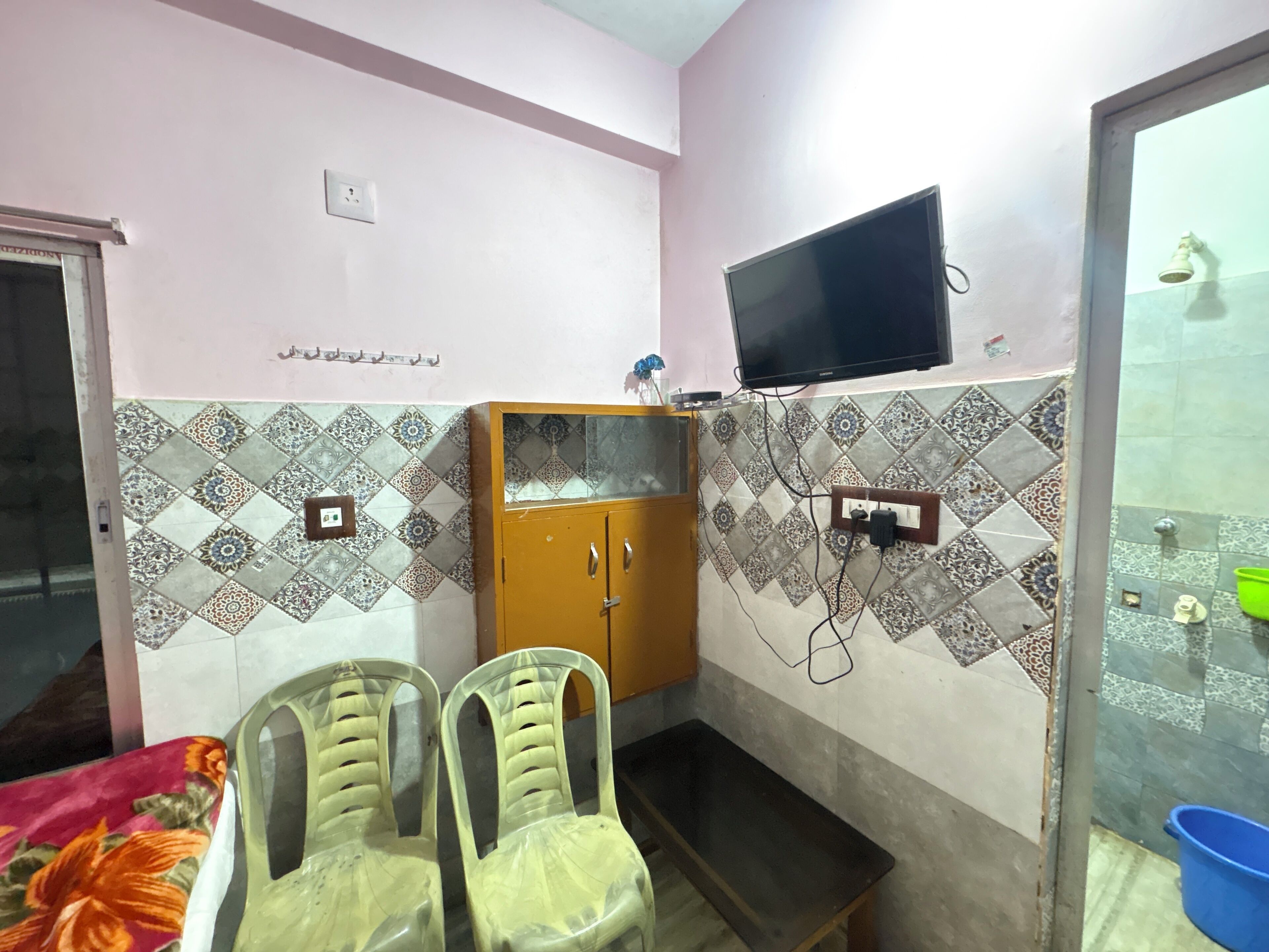 A small room with a bed, a desk, two chairs, a television, and a cabinet.