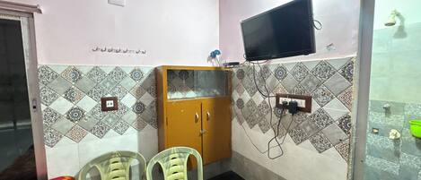 A small room with a bed, a desk, two chairs, a television, and a cabinet.