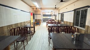 Un comedor amplio con techos altos, paredes de azulejos y una larga mesa con sillas.