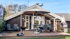 A covered outdoor patio with a dining table and chairs, a grill, and a stone oven.