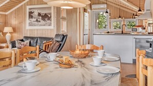 A cozy interior with a dining area, wooden furniture, and a kitchen in the background.