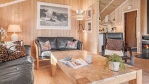 A cozy living room with a wooden ceiling, a leather sofa, a coffee table, and a fireplace.