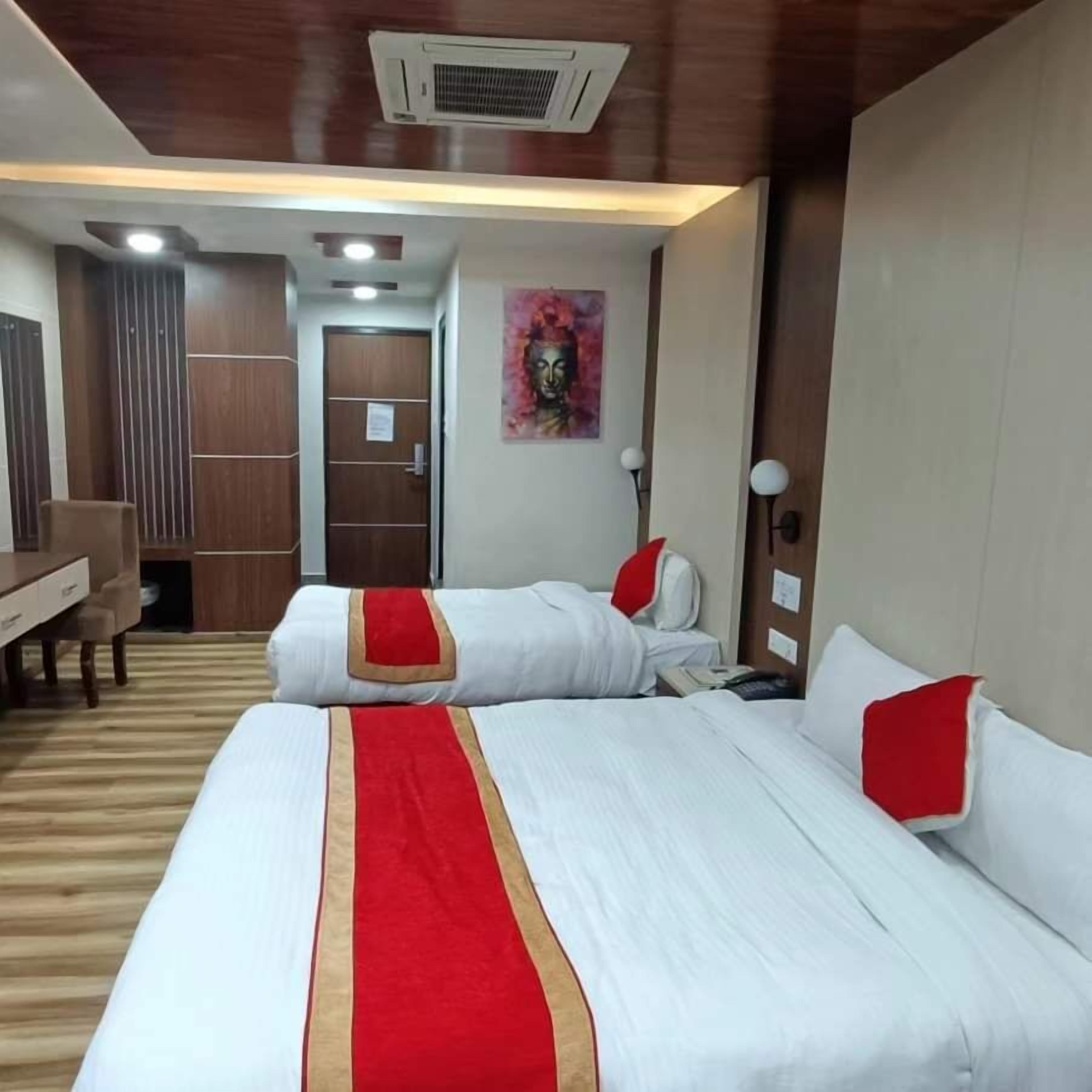 A hotel room with two beds, a desk, and a chair.