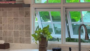 Una cocina con ventana, un fregadero, una planta en maceta y un salpicadero de azulejos.