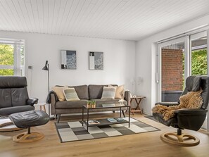 A modern living room with a sofa, two armchairs, a coffee table, and a fireplace.
