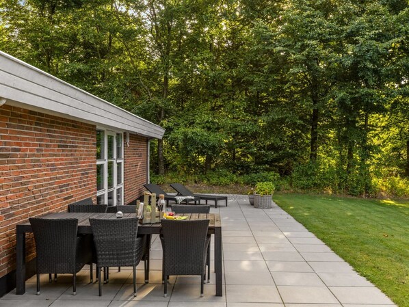 A patio with a brick wall, outdoor furniture, and a grassy area with trees.