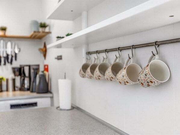 A kitchen with white cabinets, a countertop, and a hanging pot rack with decorative pots.