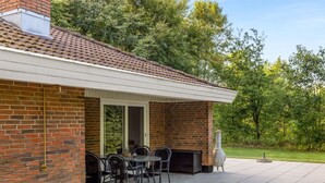 Eine Terrasse mit Ziegelmauer, überdachter Sitzgelegenheit und Grill.