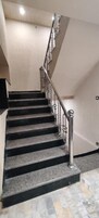 Una escalera con peldaños negros y barandilla metálica.