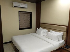 Una cama bien hecha con sábanas blancas, cabecera de madera y teléfono junto a la cama.