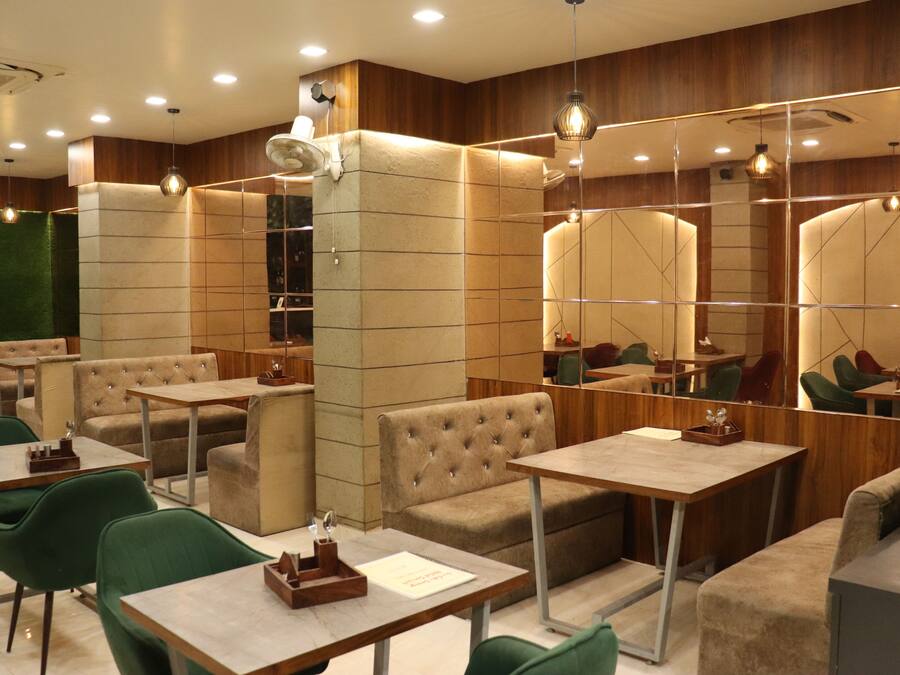 A modern restaurant with booths and tables, wooden paneling, and pendant lighting.
