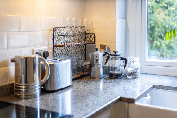 A kitchen with a granite countertop, a coffee maker, a kettle, and a glass jar.