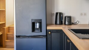 Une cuisine moderne avec un réfrigérateur noir, une machine à café et un grille-pain posés sur le plan de travail.