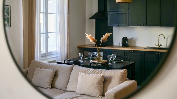 Une cuisine moderne avec des meubles de couleur sombre, un plan de travail en bois et un luminaire suspendu.