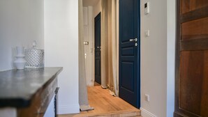 Un couloir avec un plancher en bois, une porte bleue et un mur blanc.