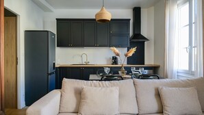 Une cuisine moderne avec des meubles de couleur sombre, un réfrigérateur noir et un plan de travail en bois.