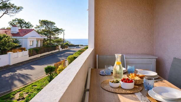 Un balcón con una mesa dispuesta para comer, con vistas a una calle y casas.
