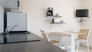 Una cocina moderna con estufa integrada, cafetera y televisor en un estante.