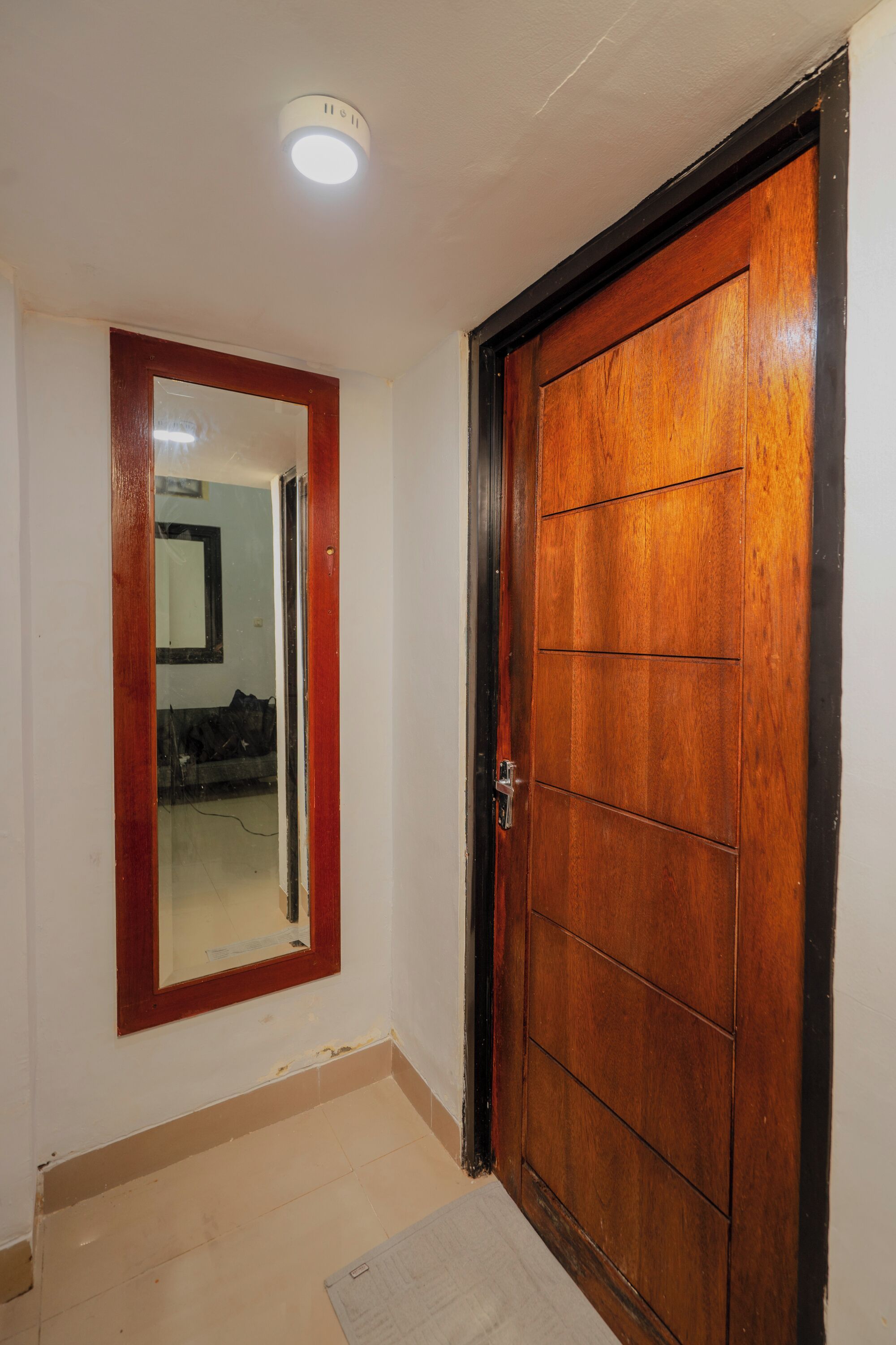 A wooden door with a black frame, a mirror above it, and a light fixture on the ceiling.