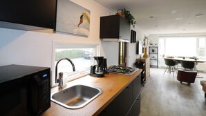 A modern kitchen with a microwave, sink, and stove. There is a window providing natural light and a view of the outside. - Atmospheric Chalet Near the Wadden Sea (Tzummarum)