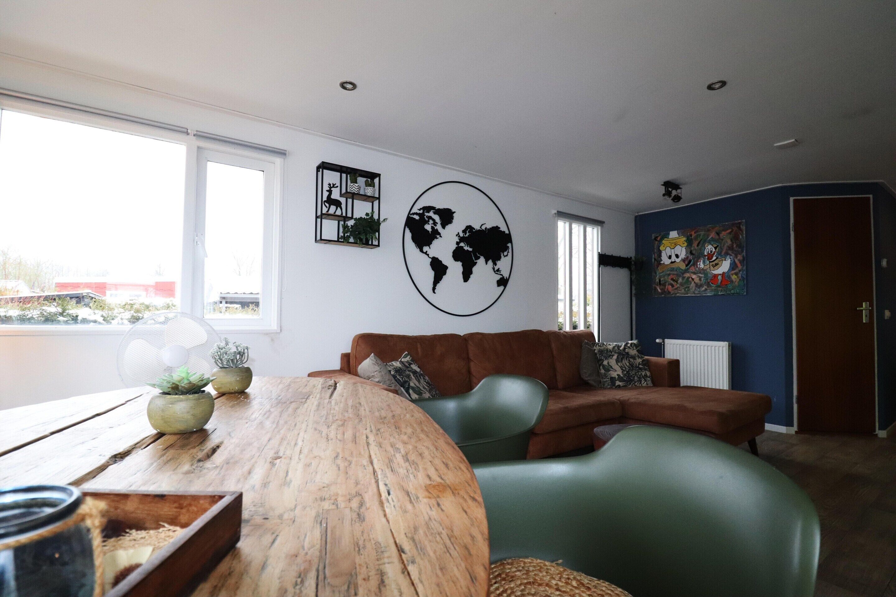 Una sala de estar moderna con una mesa de madera, un sofá verde y un mapa mundial en la pared.