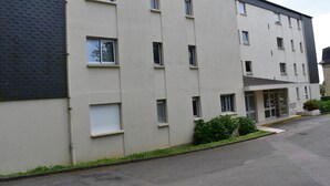 A multi-story building with a flat facade, several windows, and a small entrance area with a door and steps.