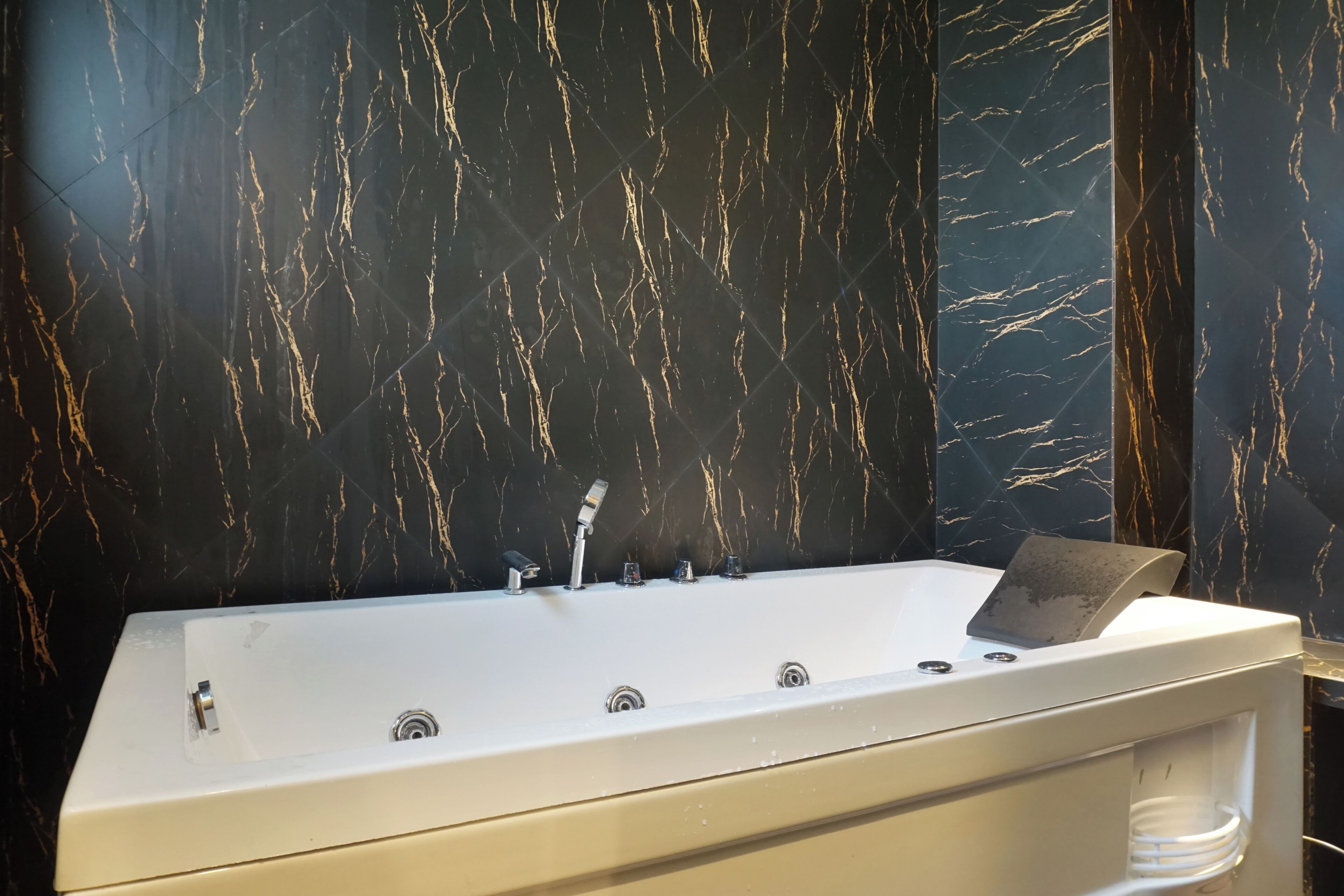 Une salle de bain moderne avec une grande baignoire, des murs en marbre et une douche intégrée.