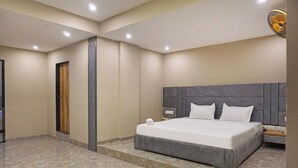 A modern hotel room with a large bed, a wooden door, and a marble floor. - Hotel Nest Inn (Mumbai)